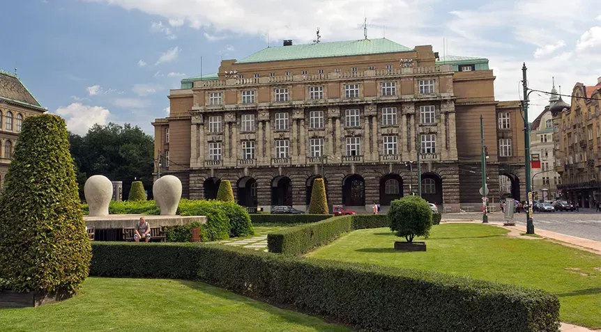 A well-tended lawn and trees in front of a historical building in Prague, where the Charles University is located.